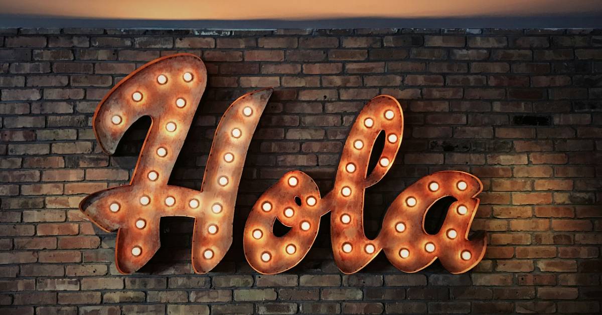 Vintage marquee-bulb sign spelling "Hola" mounted on a brick wall