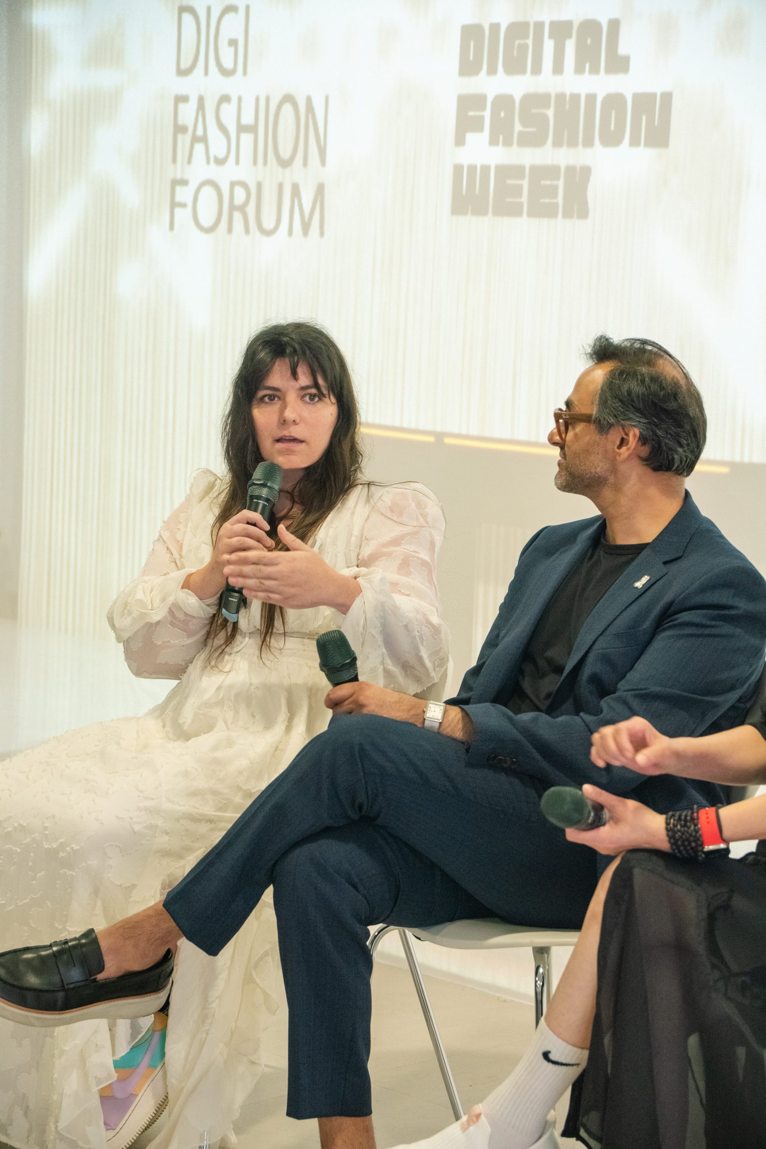 Elena Dimopoulou speaks into a microphone on a panel at Digital Fashion Week x DigiFashion Forum, Taipei